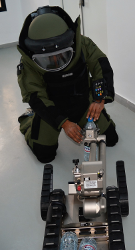 Person in einem Bombenschutzanzug bedient einen Fernlenkmanipulator