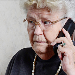 verängstigt schauende Seniorin mit einem Telefon am Ohr (verweist auf: Enkeltrick: Betrug am Telefon mit neuer Masche)